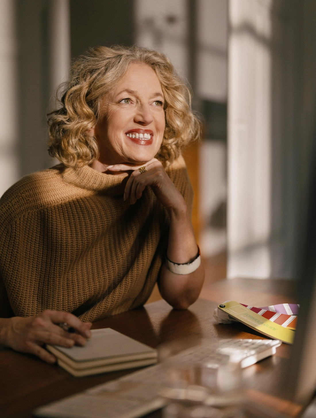 Designerin Christiane Schirmaier am Schreibtisch - lächelnd im Portrait